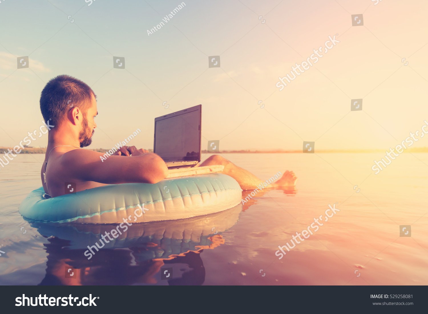 stock photo man with a laptop on inflatable ring in the water 529258081